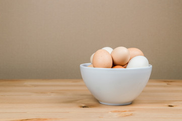Chicken eggs in a white bowl on the table with copy space