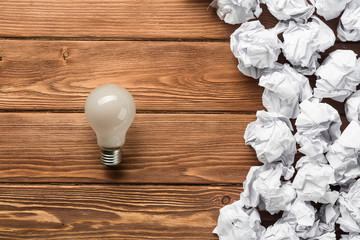 Ideological concept with wastepaper light bulb on wooden table