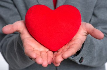 Obraz premium Close up, plush Heart in child hands. Happy Valentines Day. Teen Boy in Love holding red heart.