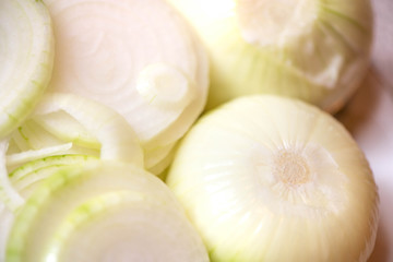 Canning fresh tomatoes with onions for winter in jelly marinade. A macro shot of group of freshly peeled onions on plate being put in jars 