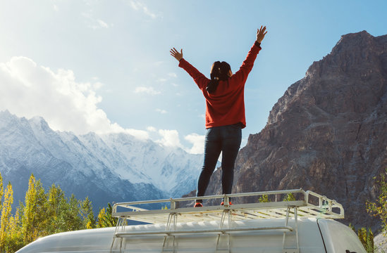 Woman standing on a van facing the beautiful mountain