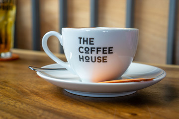 Cup of Cappuccino on a Wooden Table with Iced Tea in the Background