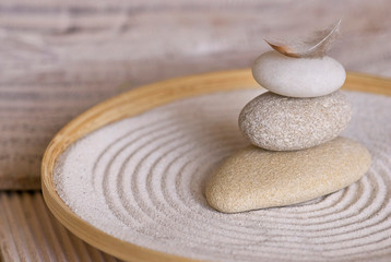 Fototapeta na wymiar Stone Cairn With Feather In Bamboo Bowl