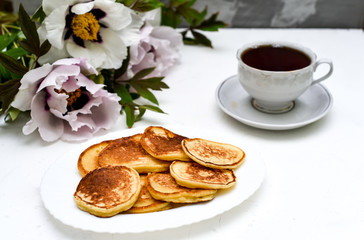 tea and pancakes on the background of beautiful pions.