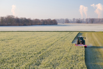 Tractor mowing the grass on the lawn in winter.