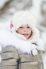 Beautiful little girl in warm jacket in winter forest
