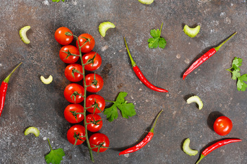 Pattern made of fresh vegetables and branch of cherry tomatoes on dark stone background. Flat lay, top view.