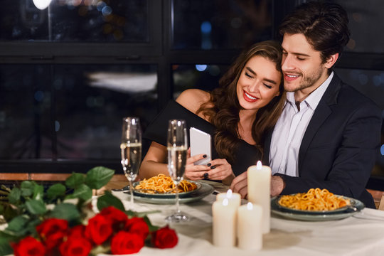 Happy couple using smartphone in restaurant