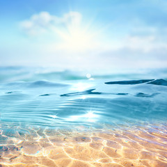 Summer landscape, nature of tropical with rays of sun light. Beautiful sun glare in wave of transparent blue water on beach against blue sky. Copy space, summer vacation concept.
