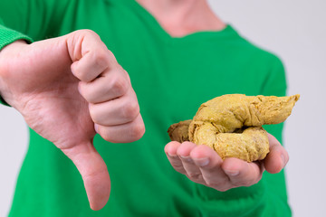 Hands of young man giving thumbs down while holding artificial poo