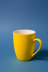 Yellow big mug isolated on blue background.