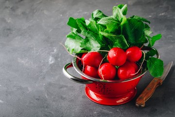 Large bunch of raw fresh garden radish  in red colander