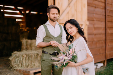 lovers in cowboy style stand near hayloft on ranch