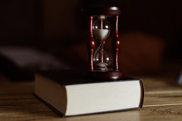 Hourglass on the book. The concept of time and reading.