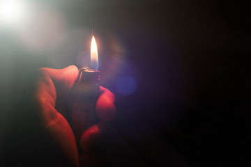 Fire lighter in male hand in the dark.