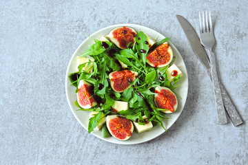 Fresh juicy salad with figs, arugula and white cheese. Healthy colorful fitness salad. Superfoods