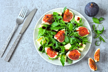 Fresh juicy salad with figs, arugula and white cheese. Healthy colorful fitness salad. Superfoods