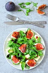 Fresh juicy salad with figs, arugula and white cheese. Healthy colorful fitness salad. Superfoods