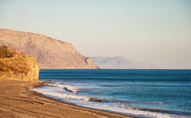 Fototapeta na wymiar The deserted coast of the Black Sea against the background of the Crimean Mountains