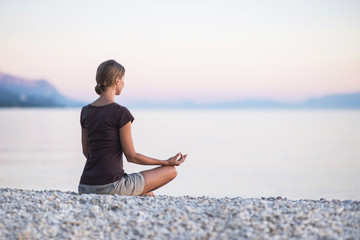 Young woman practicing yoga near the sea. Harmony and meditation concept. Healthy lifestyle