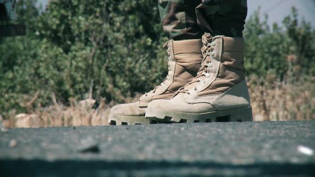 An army soldier holds a gun in his hand military boot