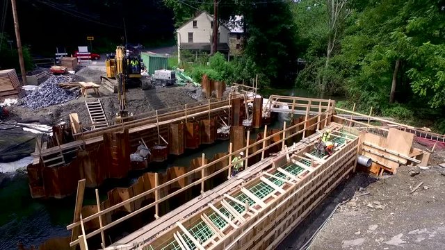 Aerial low angle pull back from working backhoe to construction workers. ?Concept: renewal, building, men working, construction, public-private partnership, infrastructure