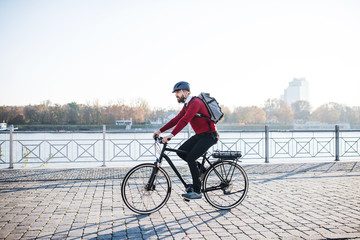 Hipster businessman commuter with electric bicycle traveling to work in city.