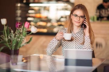Business woman with laptop and phone in cafe