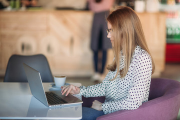 Business woman with laptop and phone in cafe. Happy young girl working