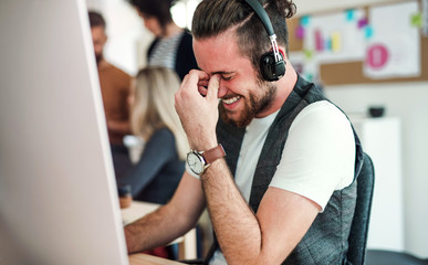 Young businessman with headphones and colleagues in a modern office.