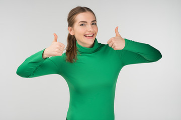 Happy girl standing against white background, holding two thumb up  - Image