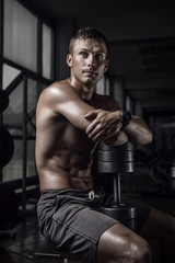Fototapeta na wymiar Fitness guy holding huge dumbbell in old rusty gym. Shallow depth of field