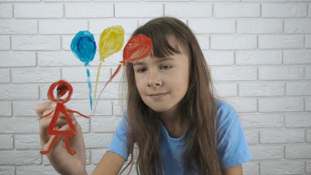 Happy child paints. Little girl draws a girl with balloons.