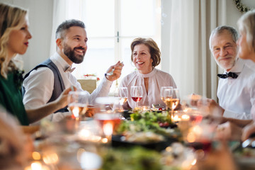 A big family sitting at a table on a indoor birthday party, eating.