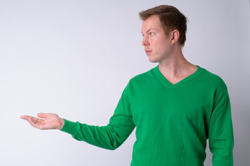 Profile view of young handsome man showing something