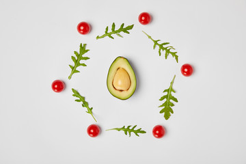 top view of avocado, arugulas leaves and cherry tomatoes on grey background
