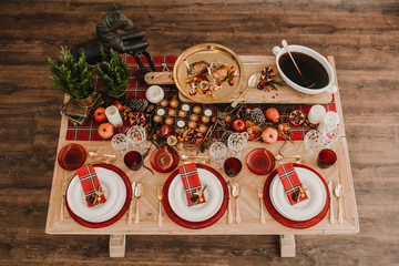 Fototapeta na wymiar .Detail photograph of a table prepared and decorated for a party diner. Autumnal and festive decoration, with wood pineapples, candles, fruits and red colors. Lifestyle. Food photography