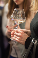 White wine glass held in hand by a woman at a presentation