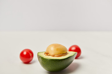 selective focus of cut avocado and cherry tomatoes on grey background