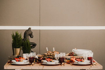 .Detail photograph of a table prepared and decorated for a party diner. Autumnal and festive decoration, with wood pineapples, candles, fruits and red colors. Lifestyle. Food photography