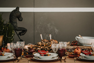 .Detail photograph of a table prepared and decorated for a party diner. Autumnal and festive decoration, with wood pineapples, candles, fruits and red colors. Lifestyle. Food photography