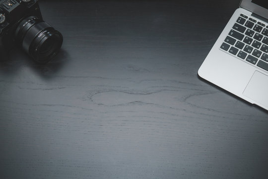 Laptop and old camera on dark wooden desk