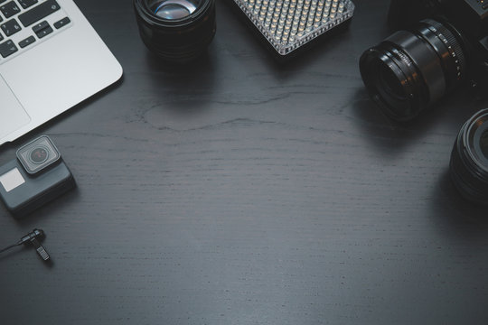 GoPro, MacBook Air, camera lens on lights on dark wooden desk