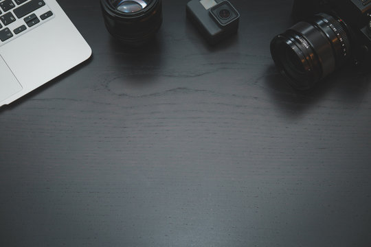 GoPro, MacBook Air, camera lens on lights on dark wooden desk