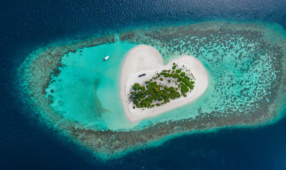 Drone Aerial view of beautiful tropical heart shaped island among blue sea water at Maldives...