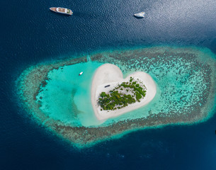 Drone Aerial view of beautiful tropical heart shaped island among blue sea water at Maldives...