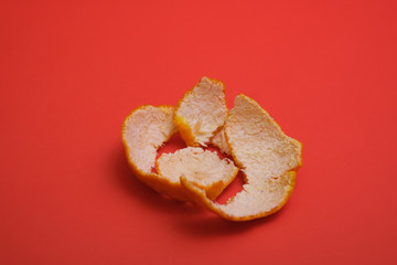 Peeled orange skin shot on a plain isolated red background.