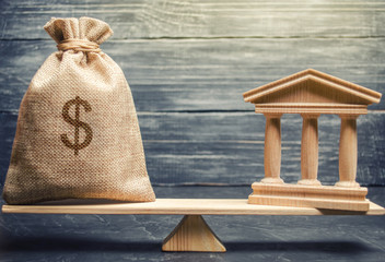 A miniature bank and money on the scales. The concept of successful investment in the bank. Credit / Loan / Deposit.The concept of dividend payments. Banking system, investment in the economy