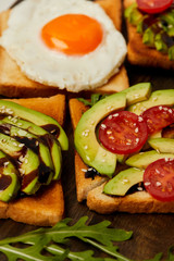 selective focus of toasts with scrambled egg, cherry tomato and avocado on wooden background