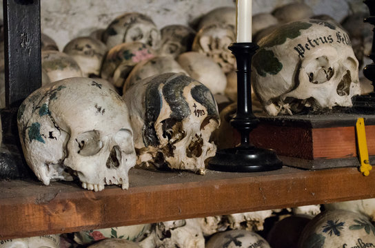 HALLSTATT, AUSTRIA - AUGUST 22, 2013: Decorated Skulls painted with names, colorful flowers and crosses in the Charnel House or Beinhaus, Hallstatt, Austria
